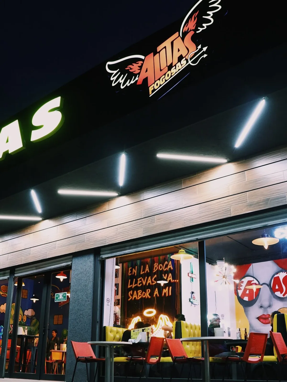 Fachada de Alitas Fogosas de noche con el logo iluminado